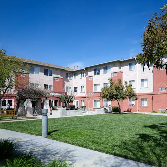 a building with red and white walls and a green lawn in front.