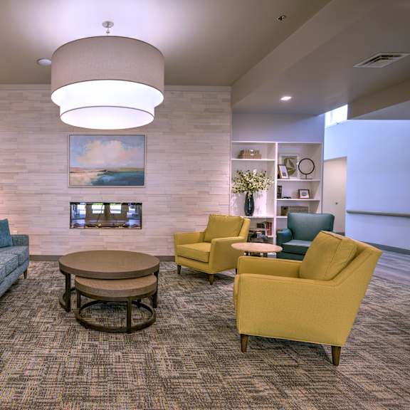 a modern waiting room with a blue couch, yellow chairs, and a coffee table.