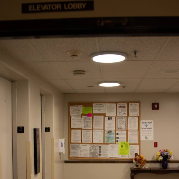 a hallway with a bulletin board and a bench with flowers on it.