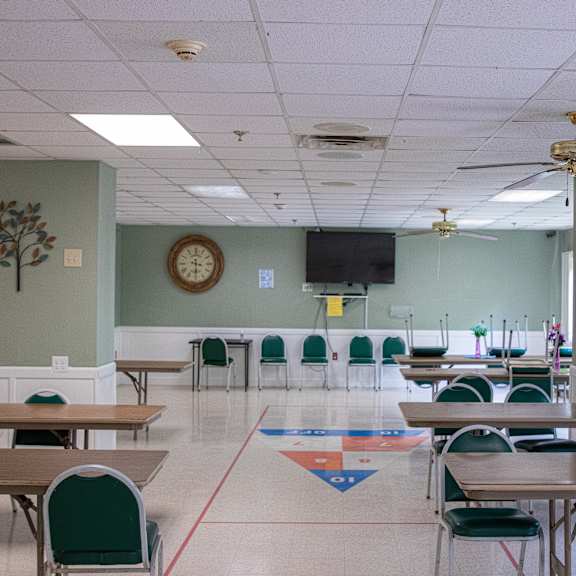 a room with tables and chairs and a clock on the wall.
