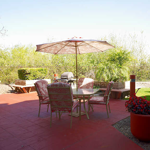 a table with chairs and an umbrella in the middle of a patio.