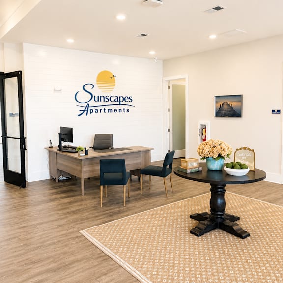 a room with a table and chairs in front of a wall with the sunstone apartments logo on it.