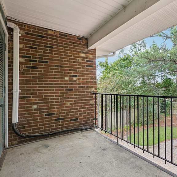 a balcony with a white railing and wooden floor.