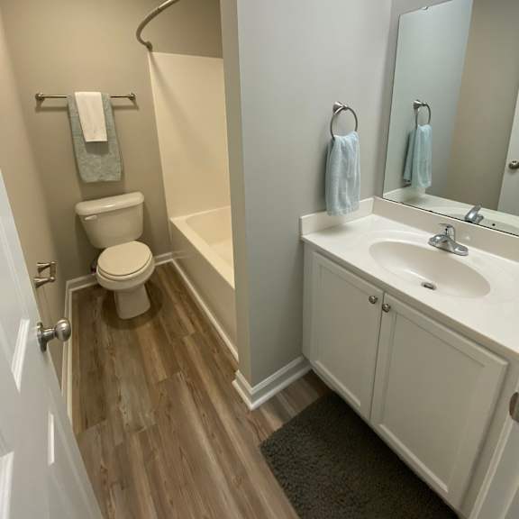 a white bathroom with a toilet, sink, and mirror.