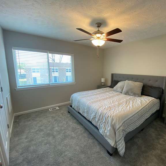 a bedroom with a bed, nightstand, and window.
