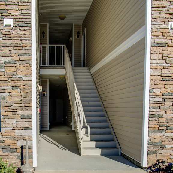 a staircase with a metal railing leads to a doorway.