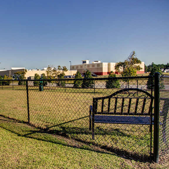 a black fence surrounds a green field with a bench on the right side.