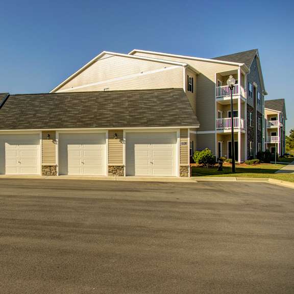 a large building with a grey roof and white walls with a parking lot in front.