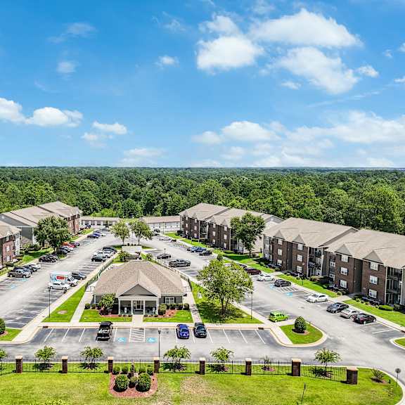 a large apartment complex with a parking lot in front.