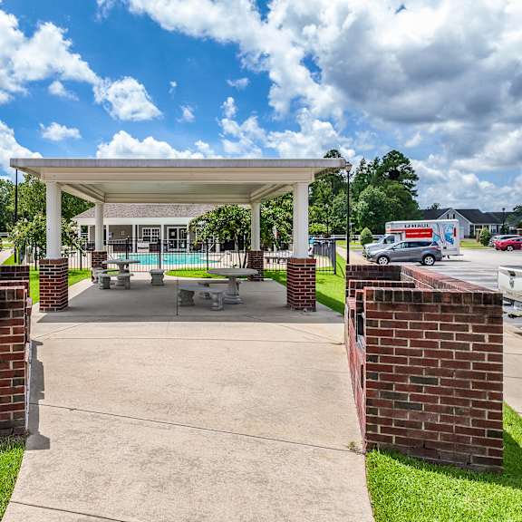 a covered picnic area with a white canopy and brick pillars.
