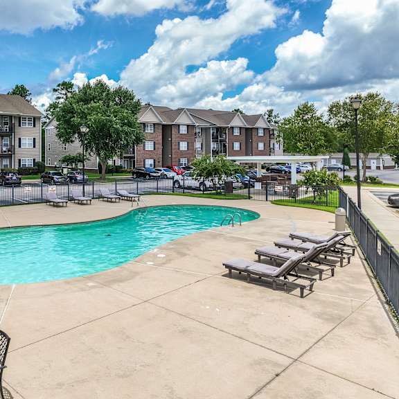 a swimming pool surrounded by chairs and apartment buildings.