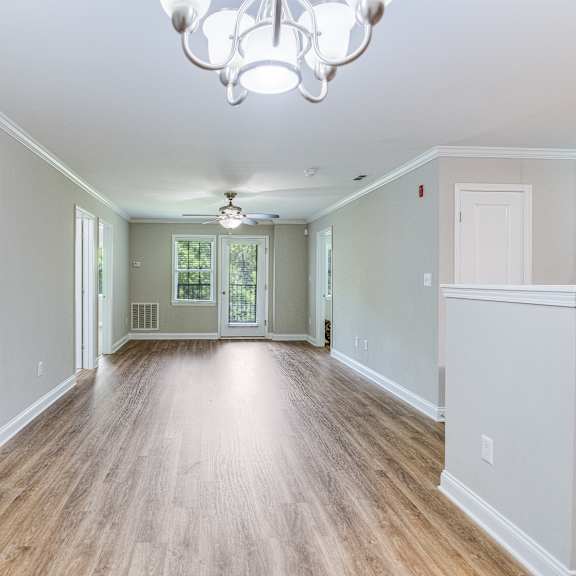 a long hallway with a chandelier and wooden floors.