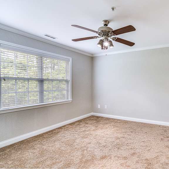 a room with a ceiling fan and a window with blinds.