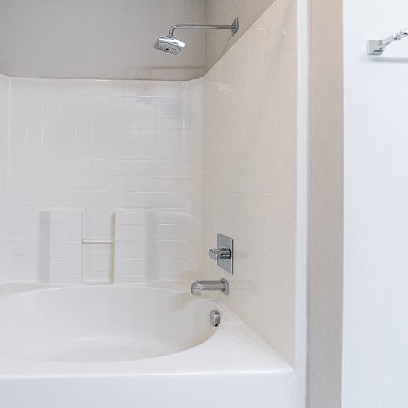 a white bathroom with a bathtub and a shower head.