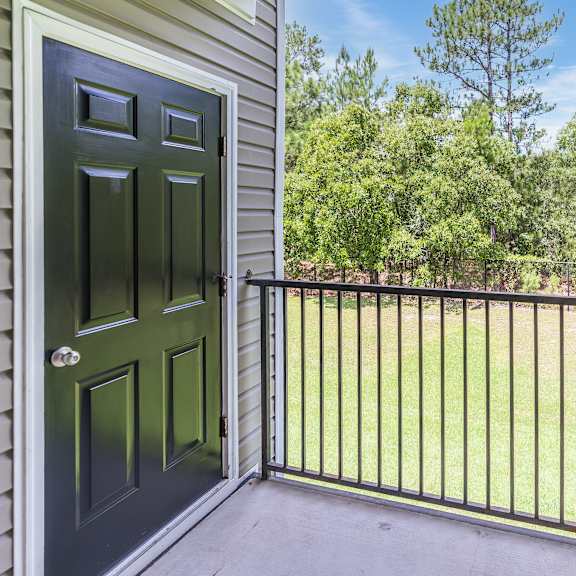 a black door is on the left of a balcony with a metal railing.