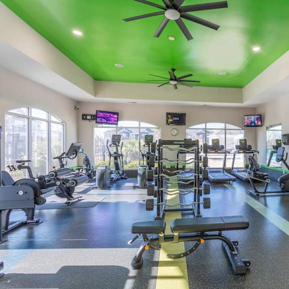 a gym with a variety of equipment including treadmills, weights, and exercise machines.