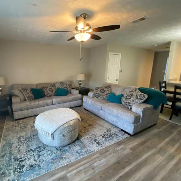 a living room with a white ceiling fan and two couches.