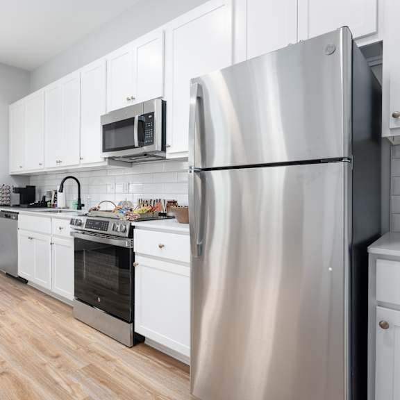 a modern kitchen with stainless steel appliances and white cabinetry.