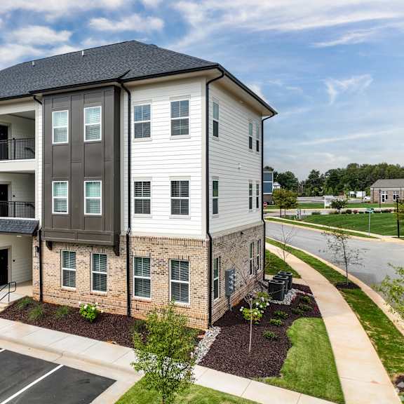 a modern apartment building with a parking lot in front.