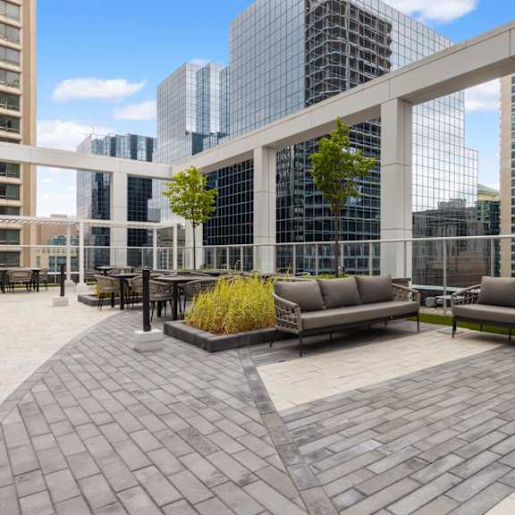 a patio with a couch and chairs with buildings in the background.