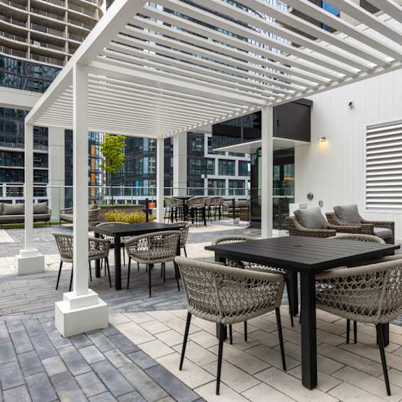 a patio with a table and chairs under a white pergola.