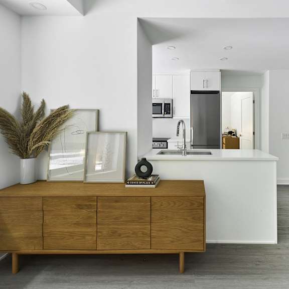 a kitchen and living room with white walls and a wooden dresser