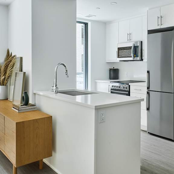 a kitchen with a white counter top and a stainless steel refrigerator