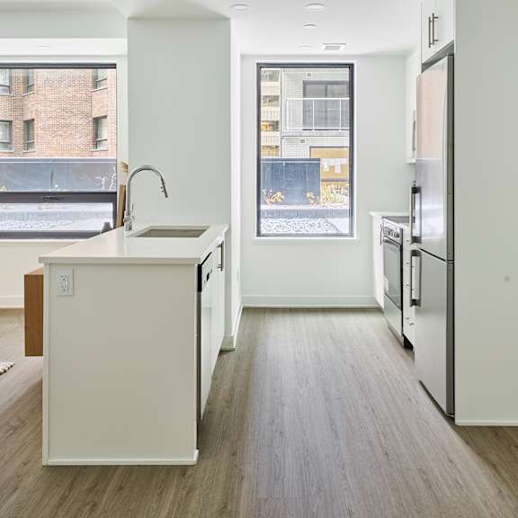 an empty kitchen with a large window and a sink and a refrigerator