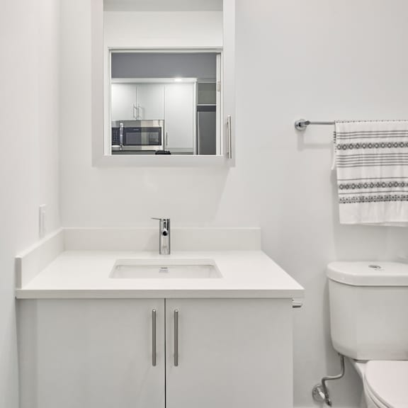 a white bathroom with a sink toilet and mirror