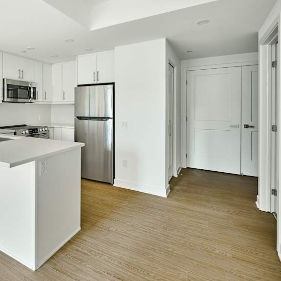 an empty kitchen with white cabinets and a stainless steel refrigerator