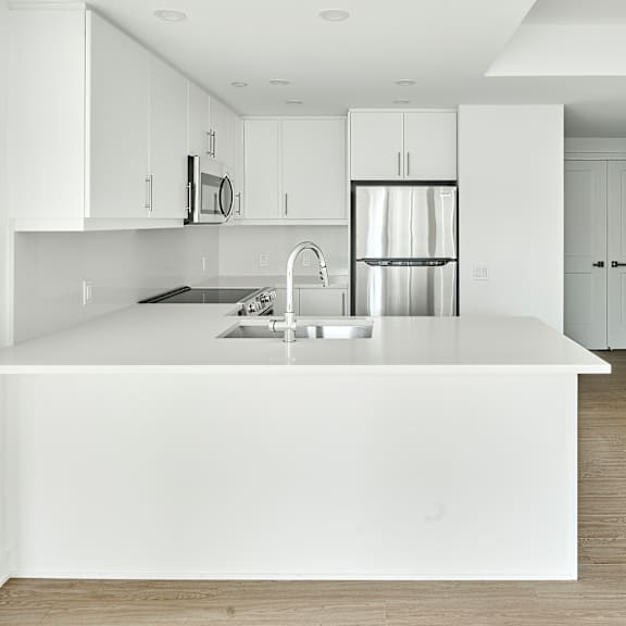 a large white kitchen with a white counter top and a white