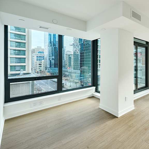 an empty living room with large windows and wood floors