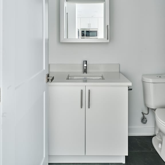 a white bathroom with a sink and mirror and a toilet