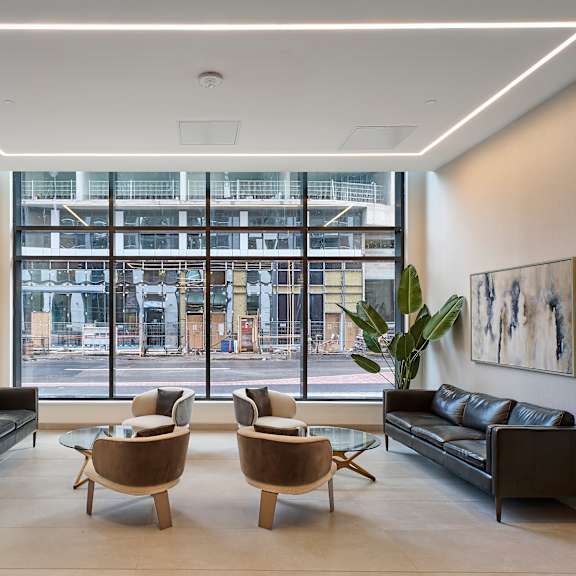 a living room with leather couches and chairs and a large window