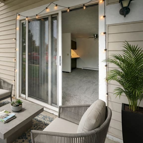 a patio with a grey sofa, a grey coffee table, and a chair with a plant on the side.