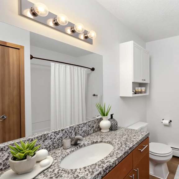 a bathroom with a white toilet, a sink, a mirror, and a towel rack.