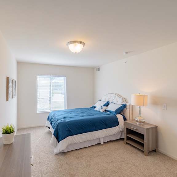 a bedroom with a bed, nightstand, and a plant.
