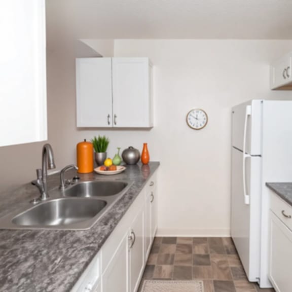 a kitchen with white cabinets and a clock on the wall.
