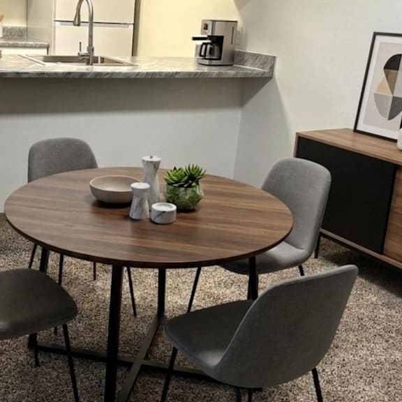 a round table with four grey chairs in a room.