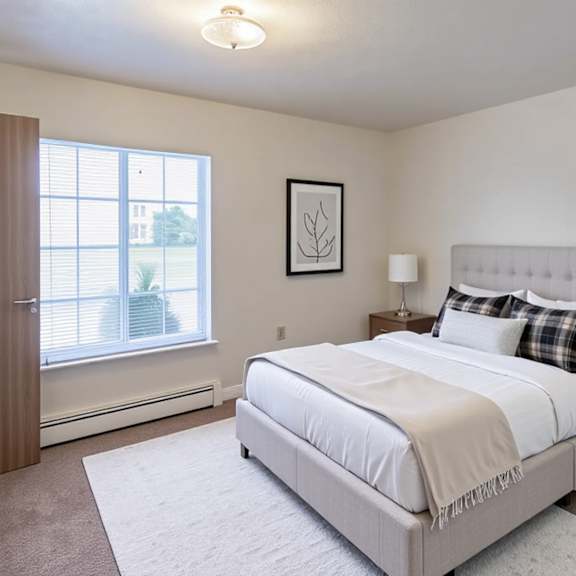 a bedroom with a large bed, nightstand, and window.