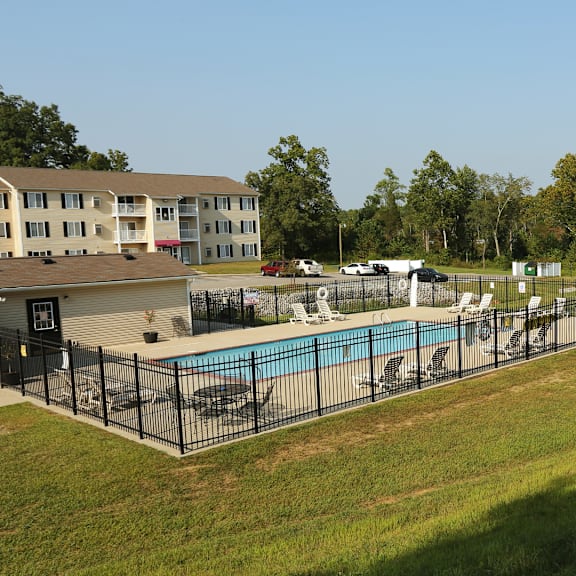 a large grassy area with a pool and a building in the background.