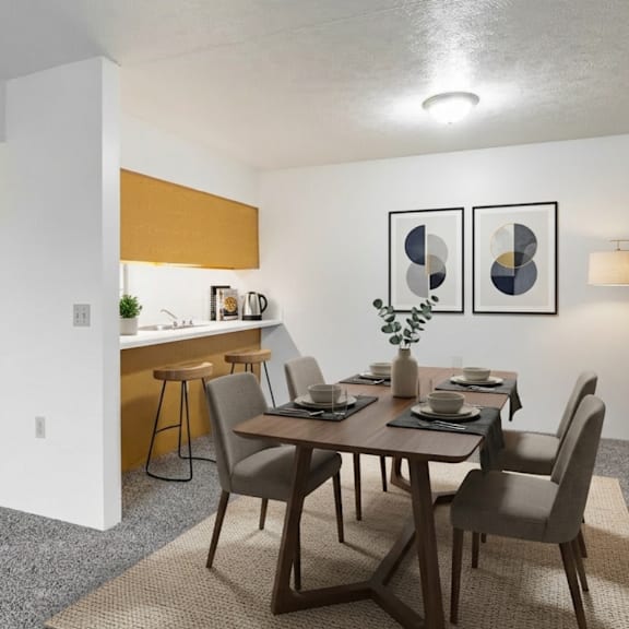 a dining room with a table set for two and a kitchen area in the background.