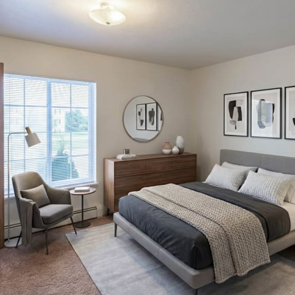 a bedroom with a bed, nightstand, chair, and pictures on the wall.
