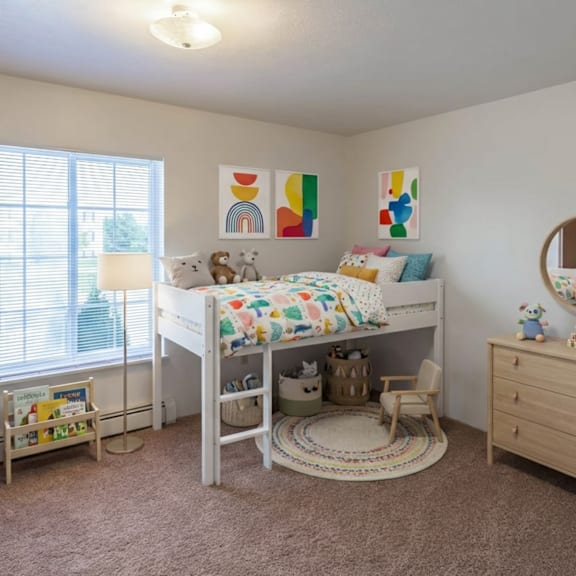 a child's bedroom with a white bed, a wooden dresser, and a round mirror on the wall.