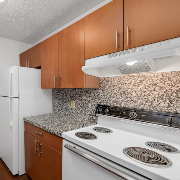 a kitchen with a white refrigerator, brown cabinets, and a granite countertop.