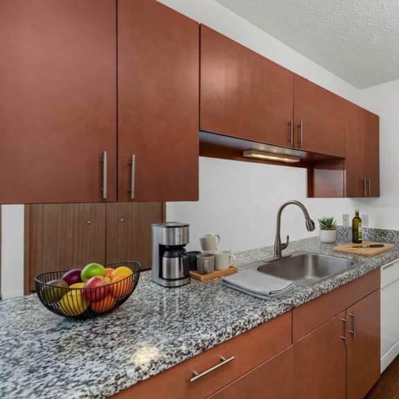 a kitchen with brown cabinets and a marble countertop.