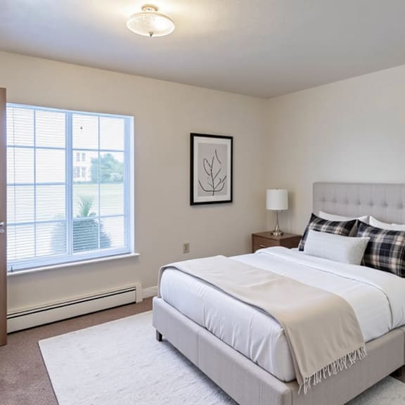 a bedroom with a large bed, a nightstand, and a window with blinds.