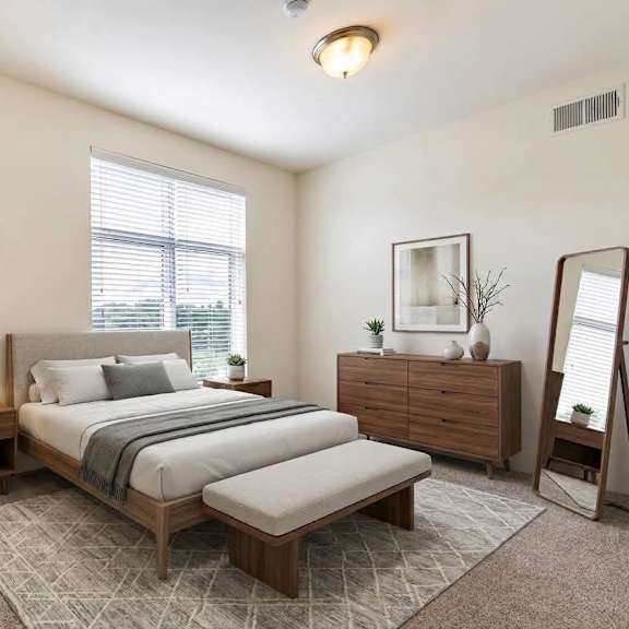 a bedroom with a bed, nightstand, chair, and mirror.