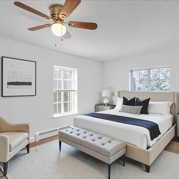 a bedroom with a bed, chair, and a ceiling fan.
