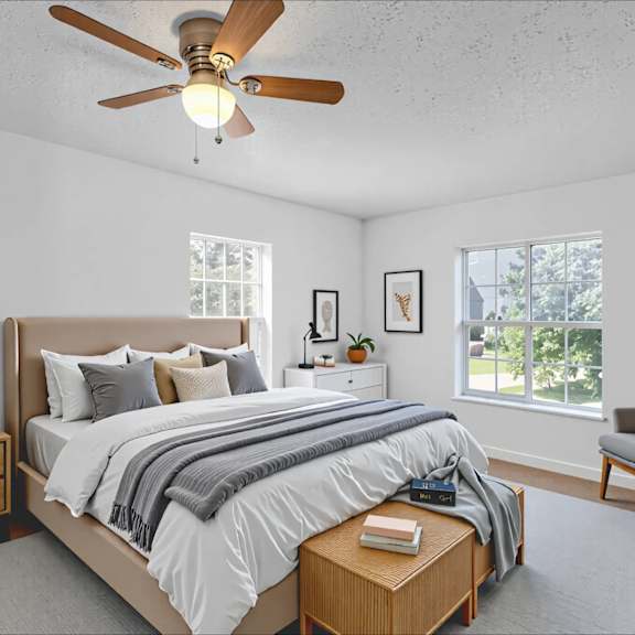 a bedroom with a bed, nightstand, chair, and a ceiling fan.
